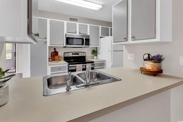 kitchen with a textured ceiling, sink, and appliances with stainless steel finishes