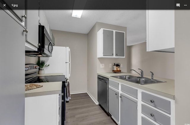 kitchen with sink, white cabinetry, stainless steel appliances, and light hardwood / wood-style flooring