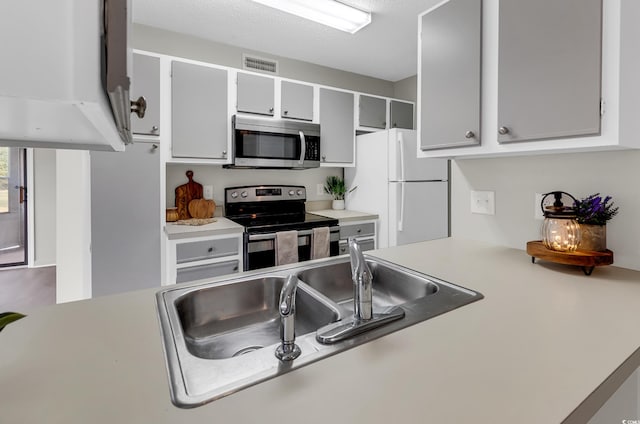 kitchen with sink, a textured ceiling, and appliances with stainless steel finishes