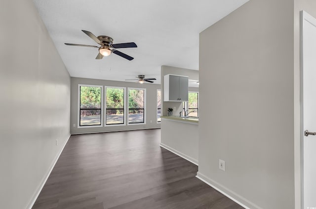 unfurnished living room with plenty of natural light, dark hardwood / wood-style floors, and ceiling fan