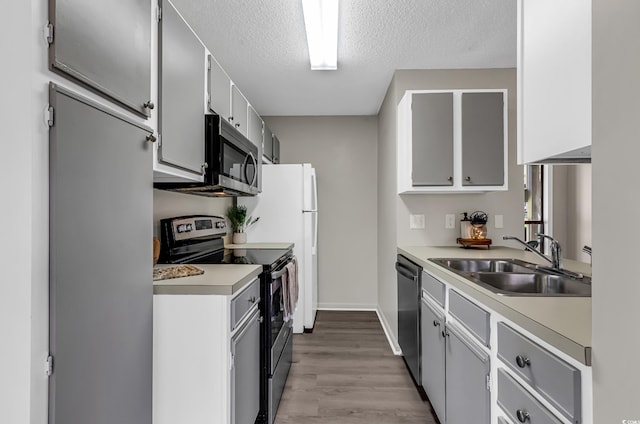 kitchen featuring white cabinetry, sink, light hardwood / wood-style flooring, a textured ceiling, and appliances with stainless steel finishes