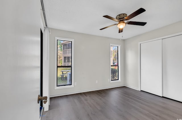 unfurnished bedroom with ceiling fan, a closet, a textured ceiling, and hardwood / wood-style flooring