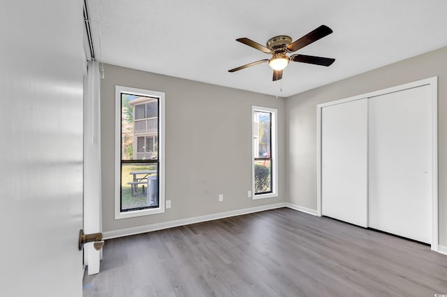 unfurnished bedroom with ceiling fan, light hardwood / wood-style floors, a textured ceiling, and multiple windows