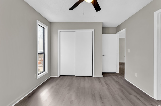 unfurnished bedroom featuring ceiling fan, light wood-type flooring, and multiple windows