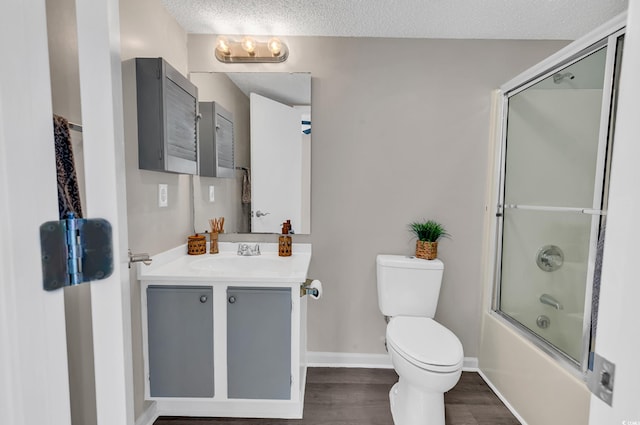 full bathroom with vanity, combined bath / shower with glass door, hardwood / wood-style flooring, toilet, and a textured ceiling