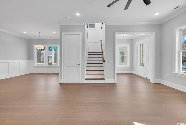 unfurnished living room featuring ceiling fan, wood-type flooring, and ornamental molding