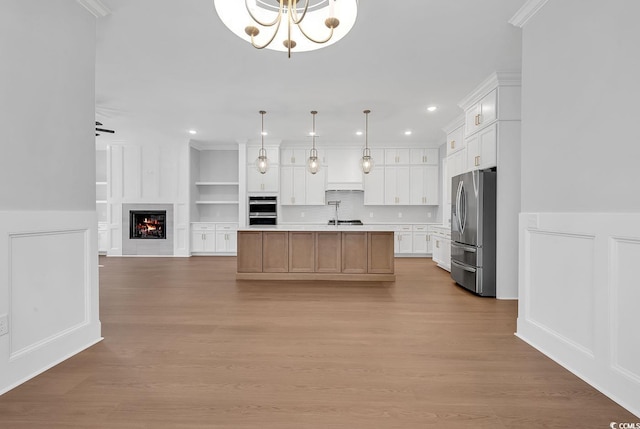 kitchen featuring a large island, stainless steel appliances, decorative light fixtures, white cabinets, and light wood-type flooring