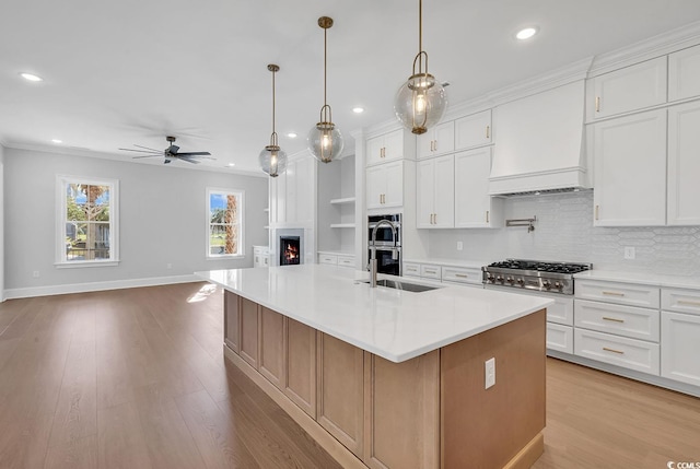 kitchen featuring white cabinets, ceiling fan, an island with sink, light hardwood / wood-style floors, and custom range hood