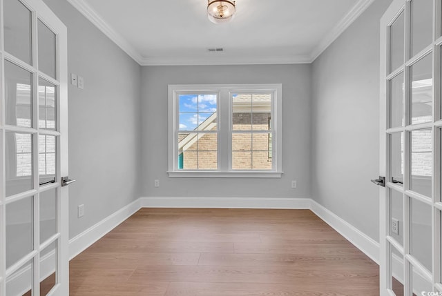 empty room with crown molding, light hardwood / wood-style flooring, and french doors