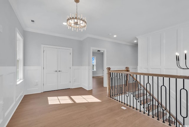 interior space with light hardwood / wood-style flooring, a notable chandelier, and crown molding