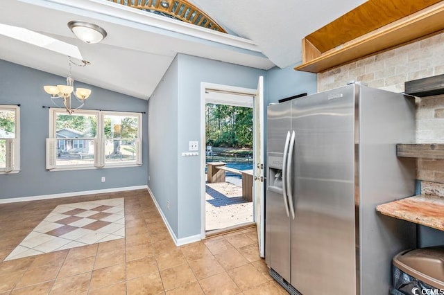 kitchen with a wealth of natural light, stainless steel fridge with ice dispenser, pendant lighting, and lofted ceiling with skylight