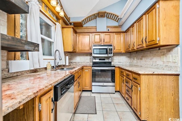 kitchen with light stone countertops, sink, stainless steel appliances, backsplash, and light tile patterned floors