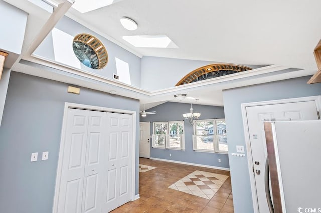 entrance foyer featuring tile patterned floors, ceiling fan with notable chandelier, and lofted ceiling with skylight