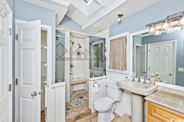 bathroom with tile patterned floors, a tile shower, a textured ceiling, tile walls, and toilet