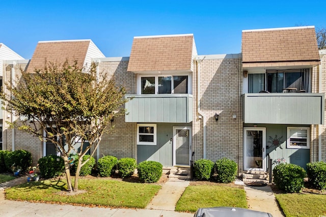 view of front of home with a balcony and a front lawn