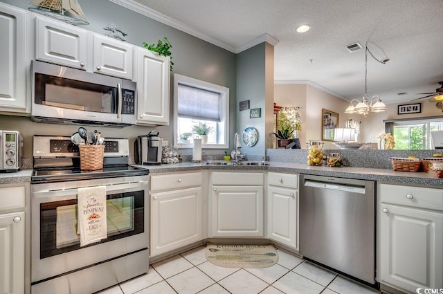 kitchen featuring stainless steel appliances, a healthy amount of sunlight, sink, and white cabinetry