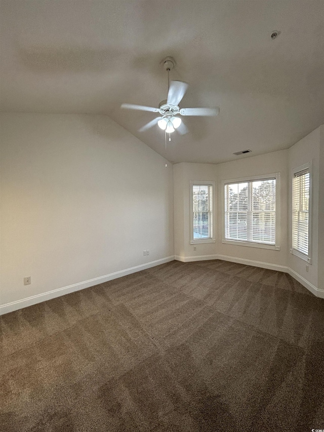 empty room with vaulted ceiling, ceiling fan, and carpet flooring