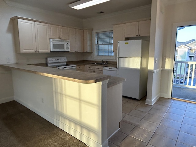 kitchen featuring white appliances, plenty of natural light, white cabinets, light tile patterned flooring, and kitchen peninsula