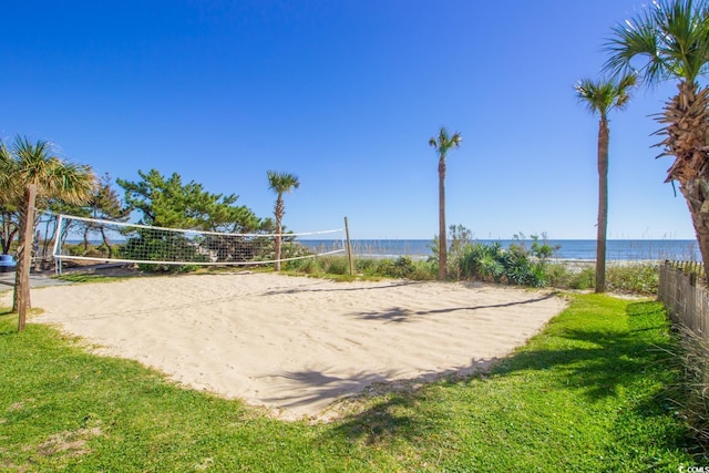 surrounding community with volleyball court, a yard, a water view, and a beach view