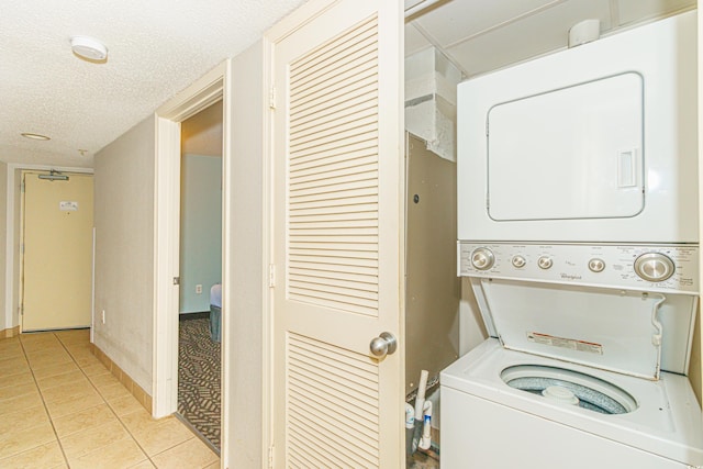 laundry area featuring a textured ceiling, stacked washer and clothes dryer, and light tile patterned flooring