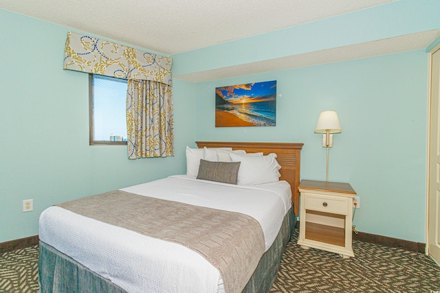 bedroom with dark carpet and a textured ceiling