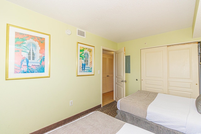 tiled bedroom featuring electric panel, a closet, and a textured ceiling