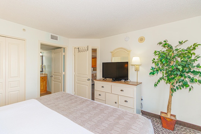 bedroom with carpet flooring, ensuite bath, a closet, and a textured ceiling