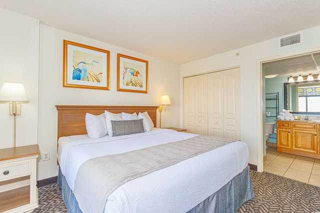 bedroom with a textured ceiling, tile patterned floors, and a closet