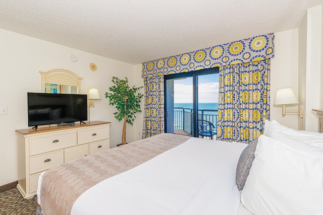 bedroom with access to outside, a water view, and a textured ceiling