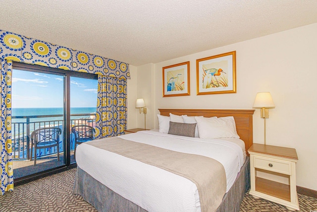 carpeted bedroom featuring access to exterior, a textured ceiling, and a water view