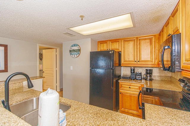 kitchen featuring light stone countertops, backsplash, a textured ceiling, sink, and black appliances