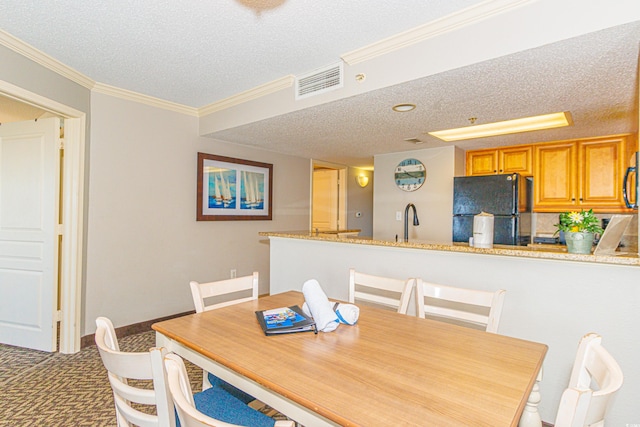 dining area featuring sink, a textured ceiling, and ornamental molding