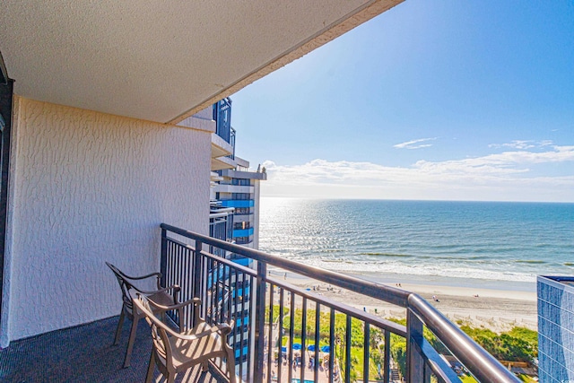 balcony with a water view and a view of the beach