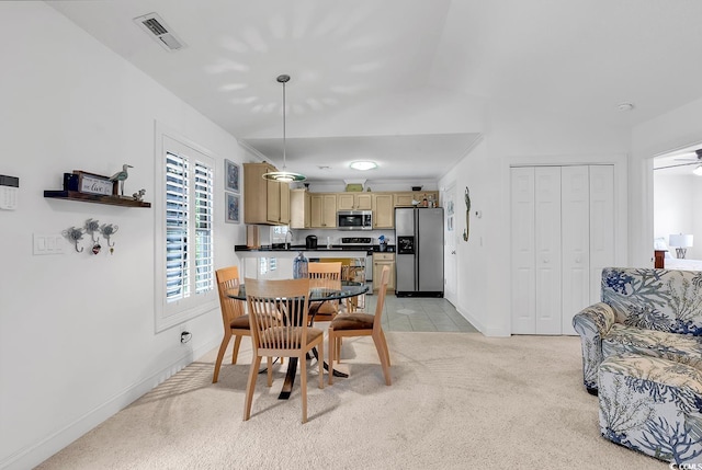 carpeted dining room with ceiling fan and vaulted ceiling