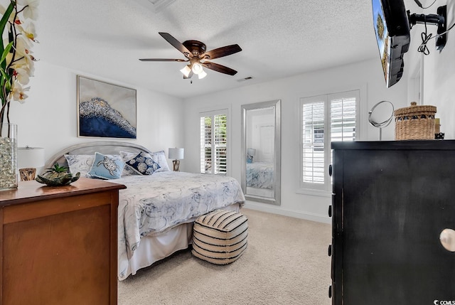 carpeted bedroom with ceiling fan and a textured ceiling