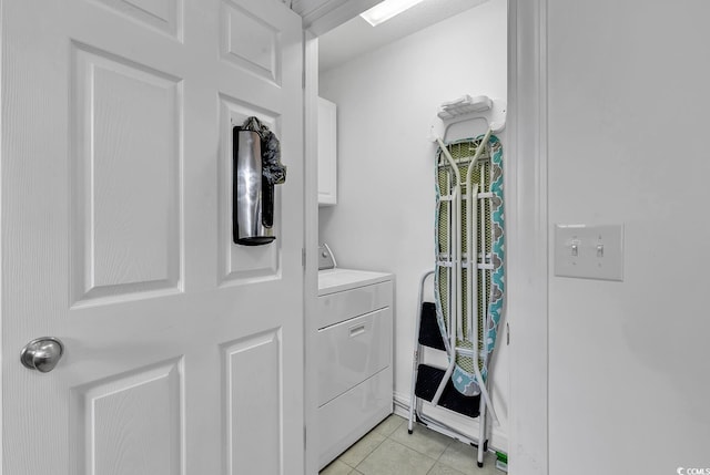 clothes washing area featuring cabinets, washing machine and dryer, and light tile patterned floors