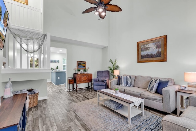 living room with ceiling fan, a high ceiling, and hardwood / wood-style flooring