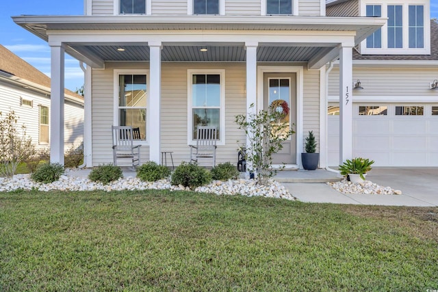 doorway to property featuring a lawn, a garage, and covered porch