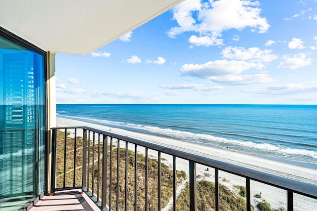 balcony featuring a view of the beach and a water view