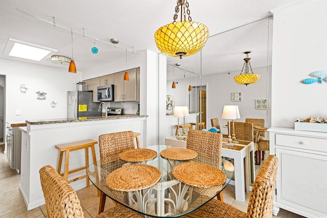 dining space featuring a skylight, light tile patterned floors, and a textured ceiling