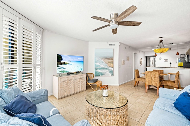 living room featuring ceiling fan, light tile patterned floors, and a textured ceiling