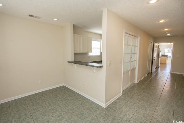 hallway featuring tile patterned floors and a textured ceiling