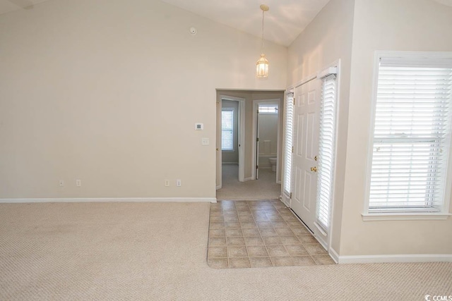 entrance foyer with a healthy amount of sunlight, light colored carpet, and lofted ceiling