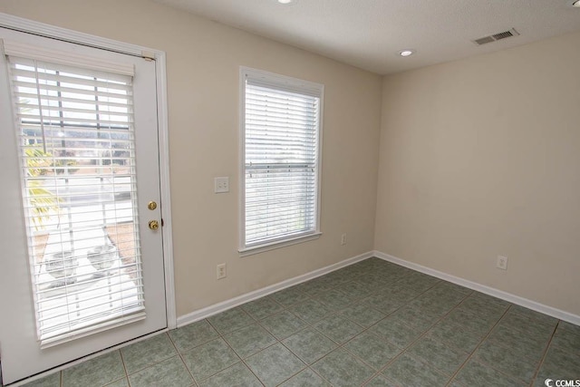 entryway with dark tile patterned flooring and a textured ceiling