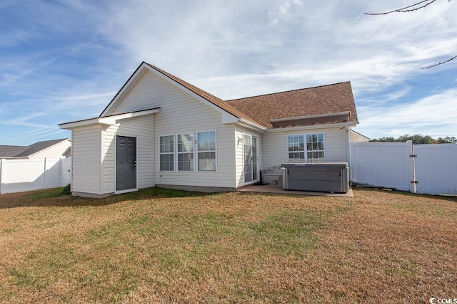 back of property featuring a yard and a hot tub