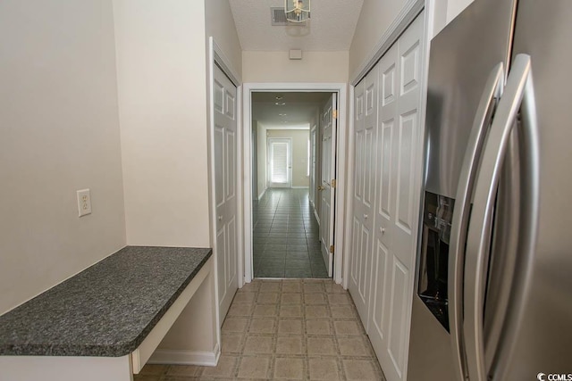 kitchen featuring a textured ceiling, white cabinets, and stainless steel refrigerator with ice dispenser