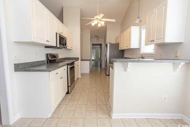 kitchen with kitchen peninsula, stainless steel appliances, vaulted ceiling, white cabinetry, and a breakfast bar area