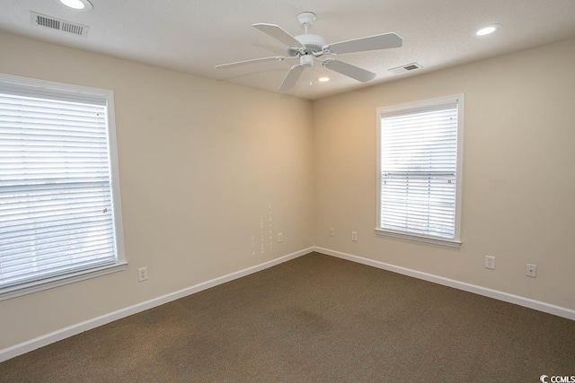 empty room featuring a healthy amount of sunlight and dark colored carpet