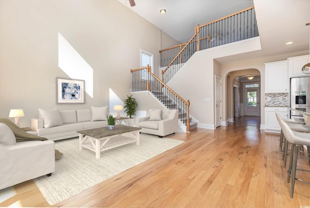 living room with a towering ceiling and light wood-type flooring