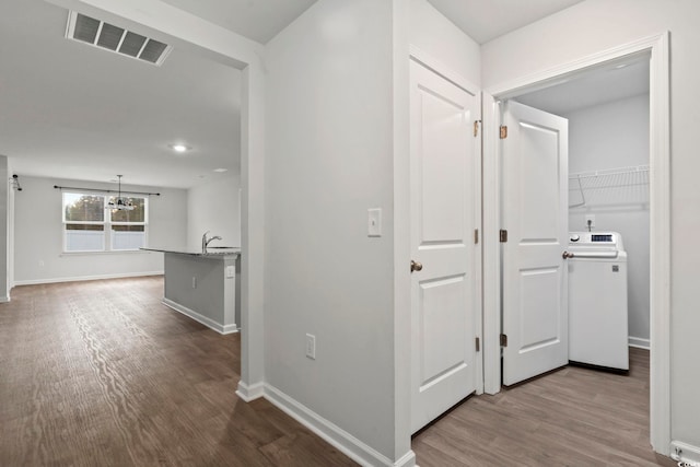 hallway with sink, wood-type flooring, and washer / dryer